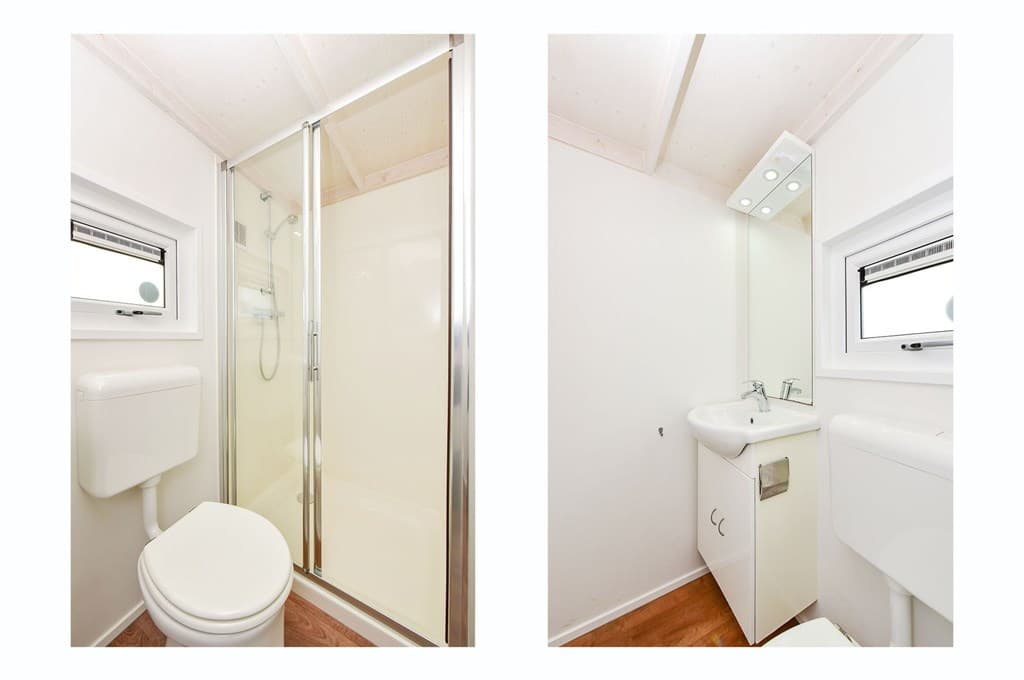 Moderne badkamer met douchecabine, toilet en wastafel in lichte kleurstelling met houten vloer.