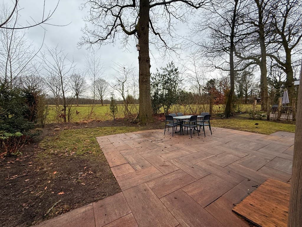 Tegeltuin met een eetset en uitzicht op een grasveld en bomen op EuroParcs Resort De Utrechtse Heuvelrug.