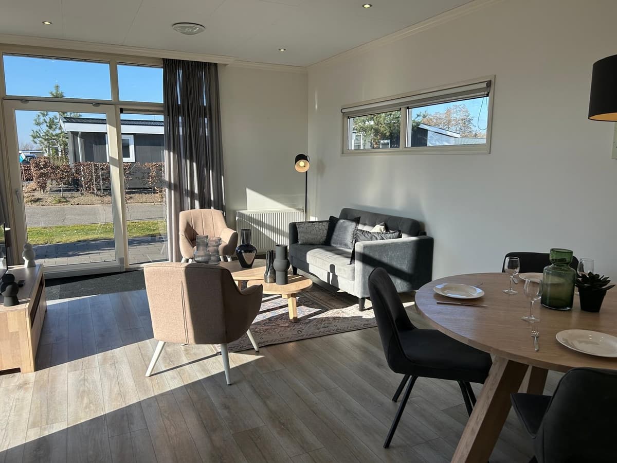 Lichte woonkamer met zithoek, eettafel en uitzicht op buitenruimte met moderne inrichting en raampartijen