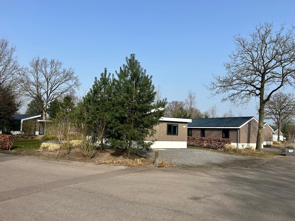 Vakantiewoning met groene accenten en bestrating in EuroParcs Zuiderzee, omgeven door bomen en rustige omgeving