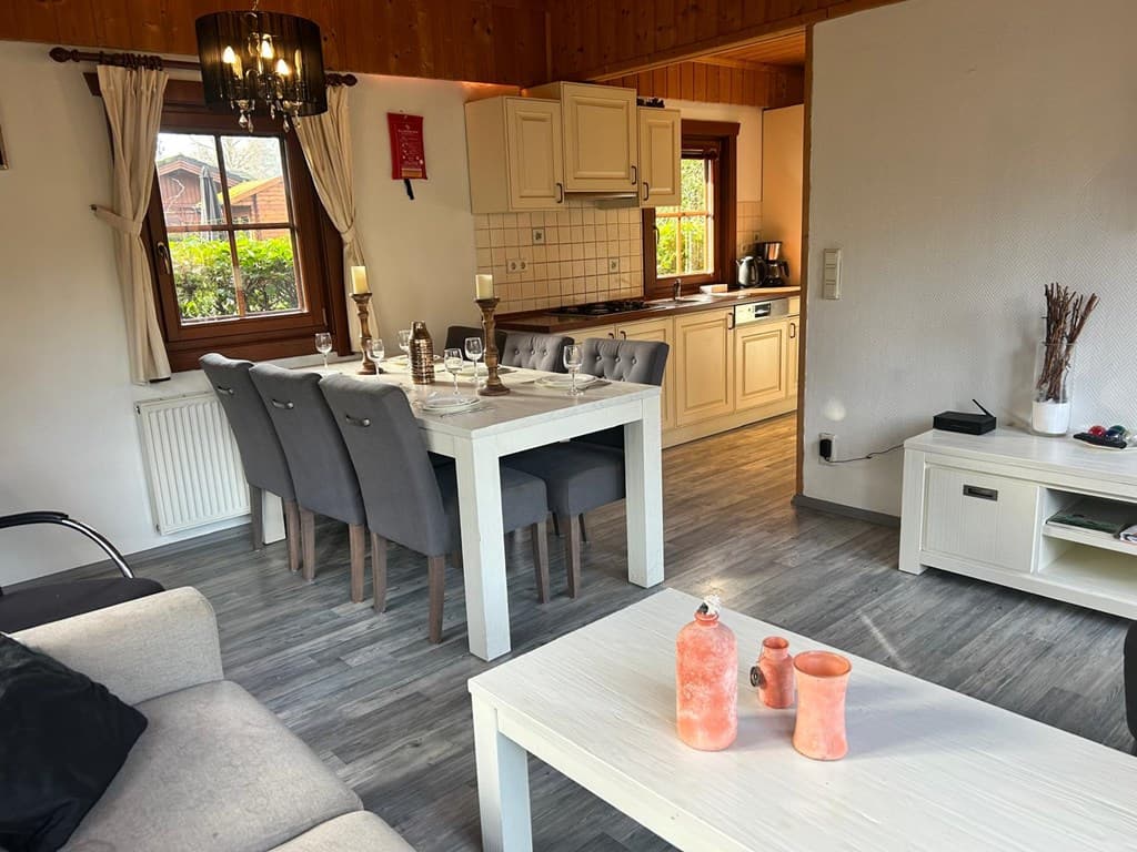 Eetkamer met een tafel en zes stoelen, open keuken, gezellige zithoek met bank en salontafel.