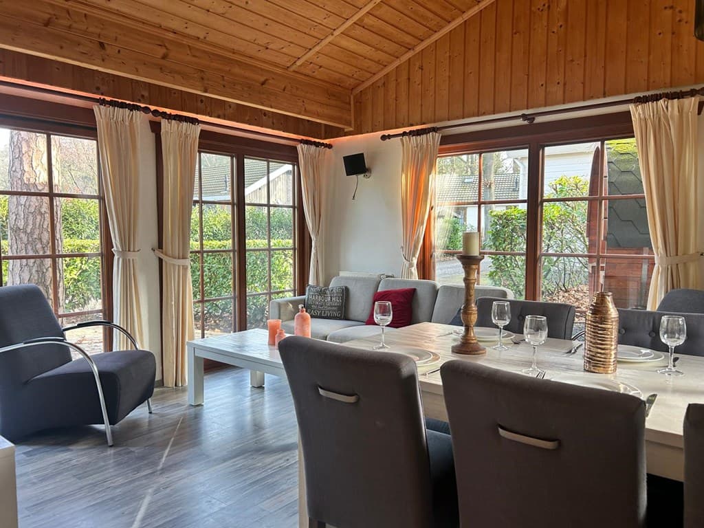 Gezellige eet- en woonkamer met houten plafonds, grote ramen en stijlvolle meubels in EuroParcs De Achterhoek, Lochem