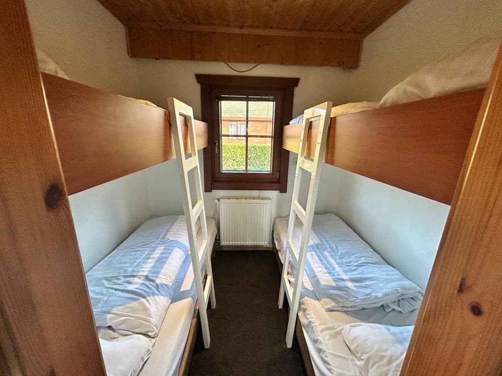 Slaapkamer met twee stapelbedden en raam met uitzicht op de buitenruimte.