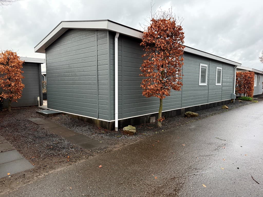 Grijze vakantiewoning met leiendak en een onderhoudsarme tuin met grind, gelegen aan een verharde weg