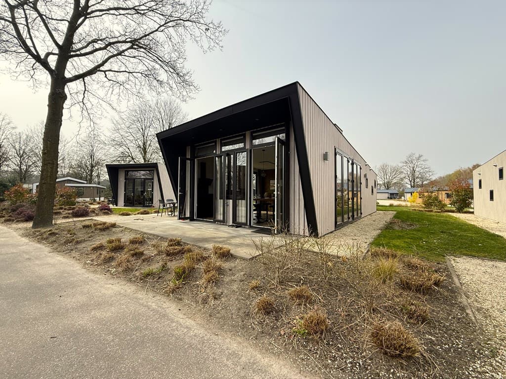 Moderne vakantiewoning met grote ramen, voortuin en grindpad in EuroParcs Kaatsheuvel.