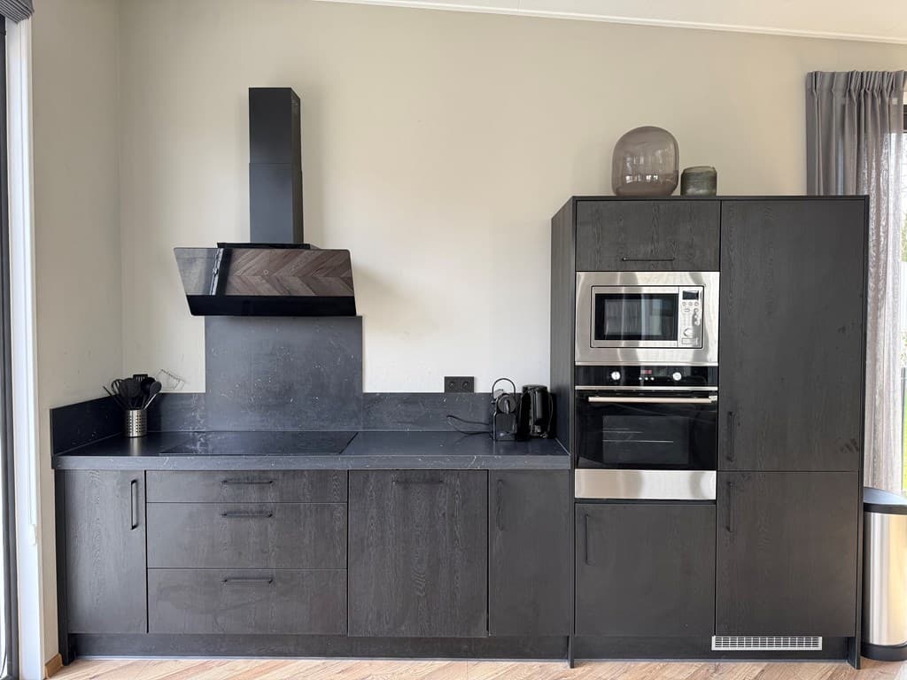 Moderne keuken met zwarte kasten, inductiekookplaat en een oven in EuroParcs Kaatsheuvel.