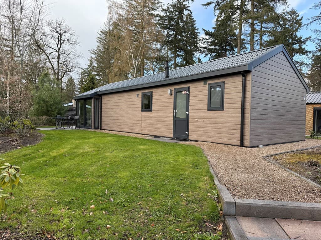 Een moderne vakantiewoning met een houten gevel en een groene tuin bij EuroParcs Resort De Utrechtse Heuvelrug.