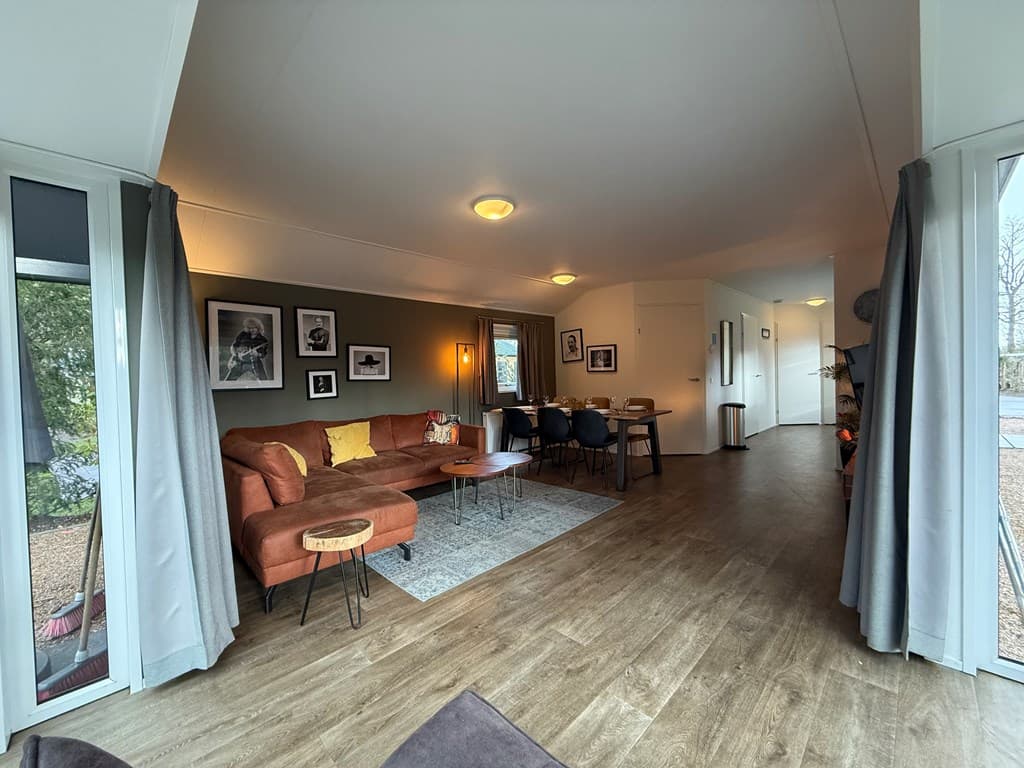 In een moderne vakantiewoning met een zit- en eethoek, grote ramen en houten vloeren.