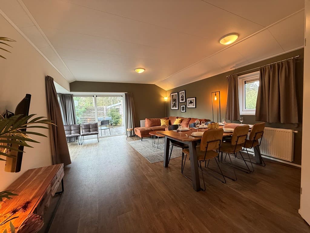 Huiselijke eet- en woonkamer met grote deuren naar een terras, moderne meubels en sfeervolle verlichting
