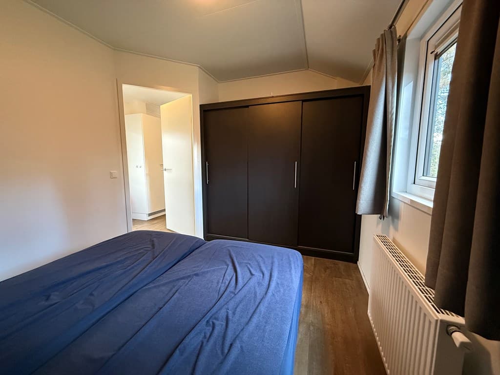 Slaapkamer met twee eenpersoonsbedden, een inbouwkast en een raam met gordijnen.