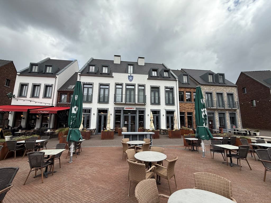 Uitzicht op de gevels van gebouwen in Dormio Resort Maastricht met terrassen en parasols in de voorgrond