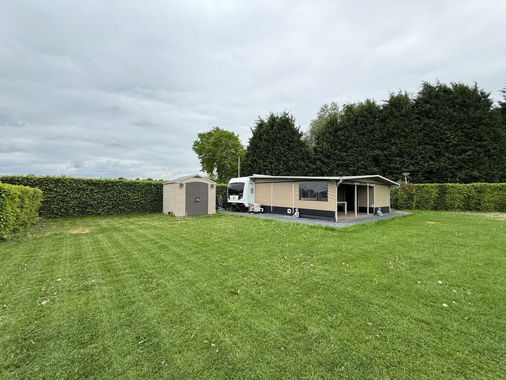 Vakantiewoning met veranda en schuur op een ruime, groene locatie omgeven door hagen en een grasveld