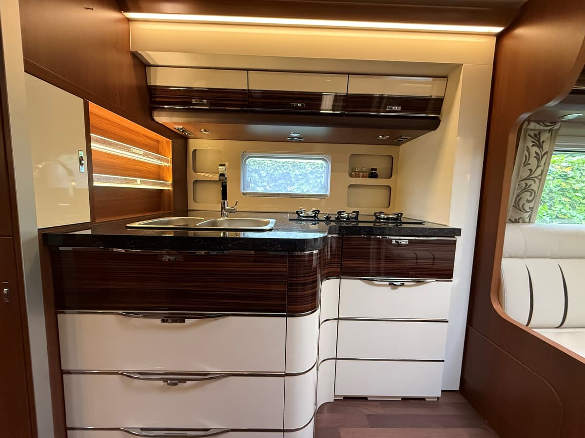 Moderne keuken met donker blad, gasfornuis, kastruimte en grote ramen voor natuurlijk licht