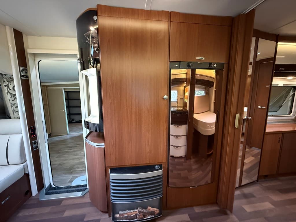 Ingericht interieur met houten kasten, een kachel en een spiegelkastje zichtbaar aan de muur.