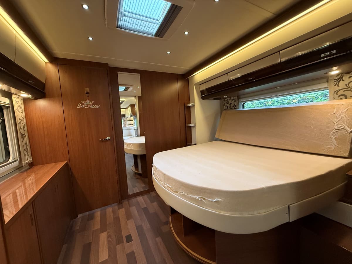 Slaapkamer met een tweepersoonsbed, opbergkasten en verlichting, in een houten interieur met moderne afwerking