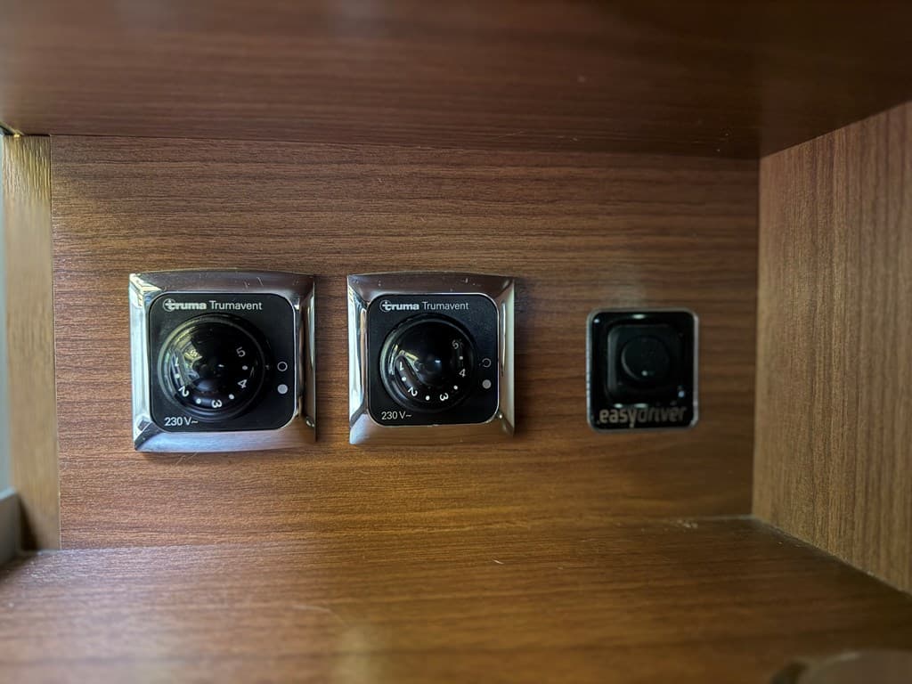 Afbeelding van een houten paneel met twee draaiknoppen en een schakelaar voor elektrische bediening
