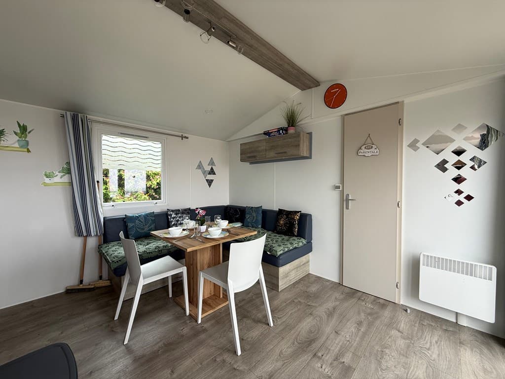 Gezellige woonkamer met eettafel, bank en decoraties aan de wand in een vakantiewoning.