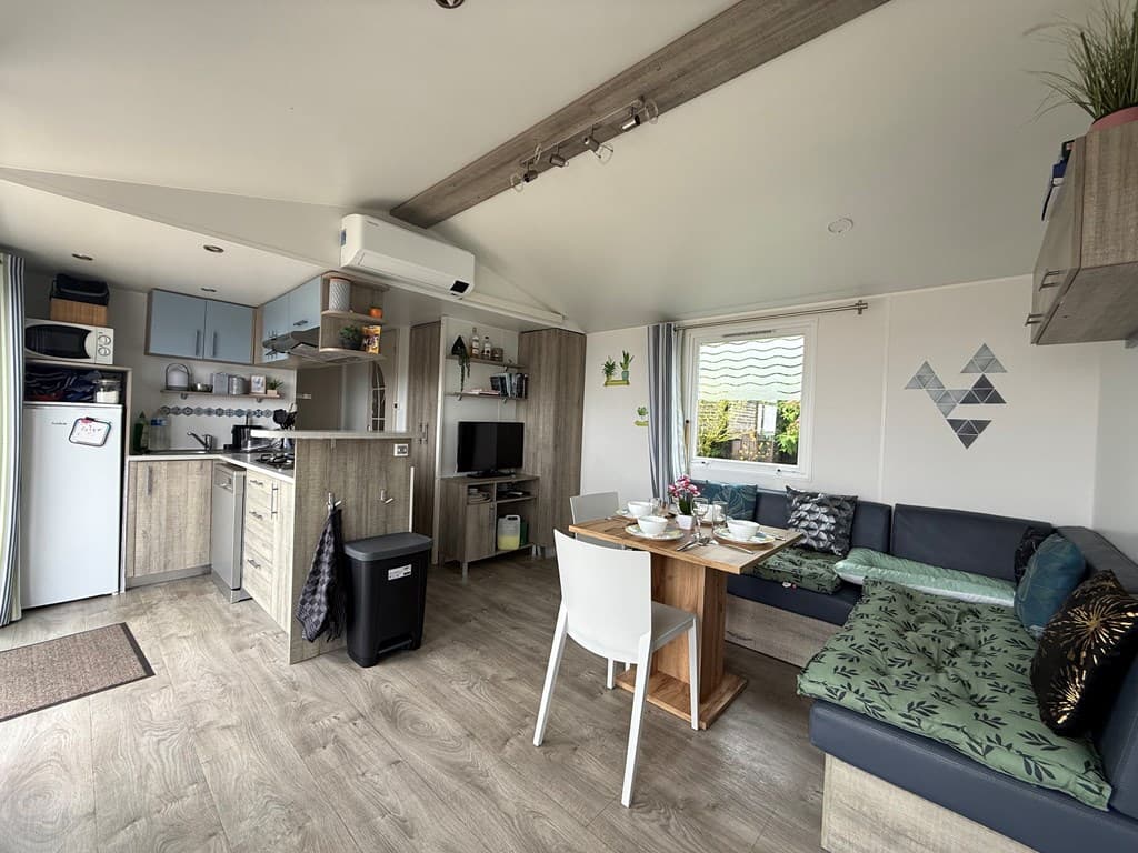Gezellige woonruimte met open keuken, eettafel en comfortabele zithoek met groene accenten.