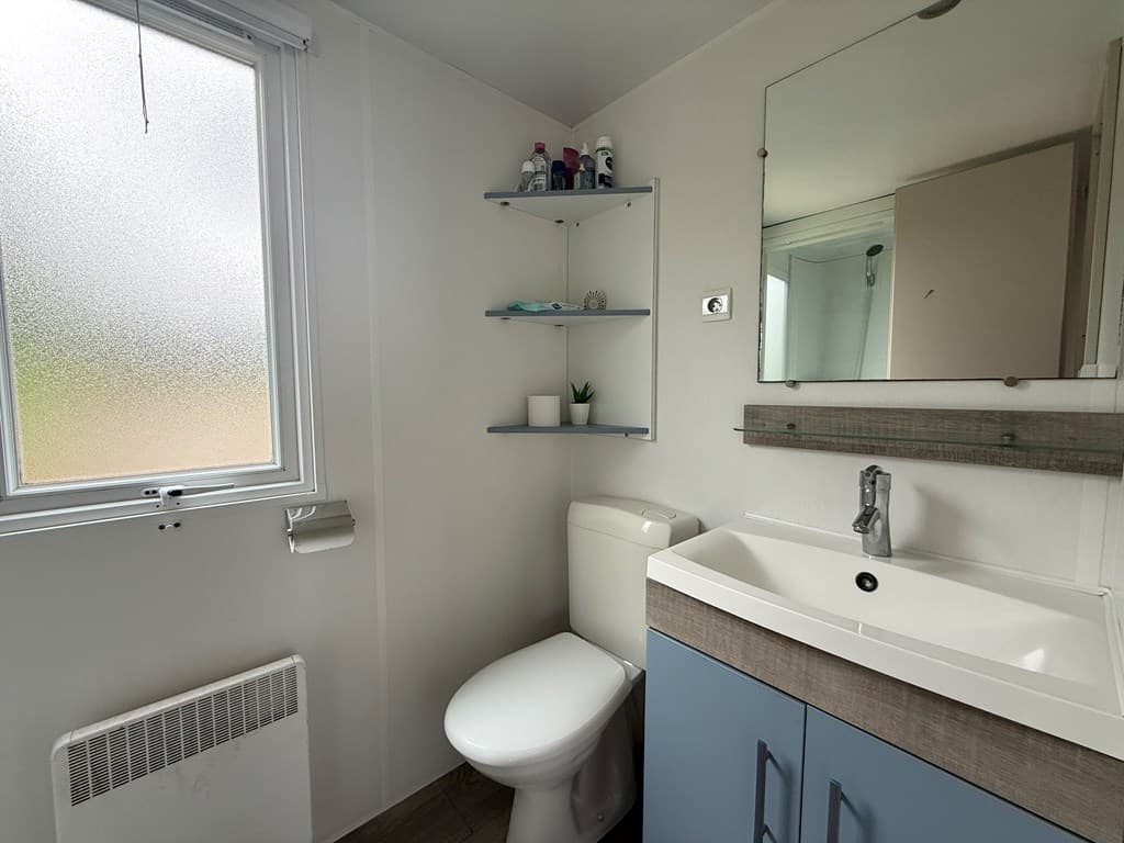 Moderne badkamer met toilet, wastafel en spiegel, ingebouwde planken en een raam met lichtinval
