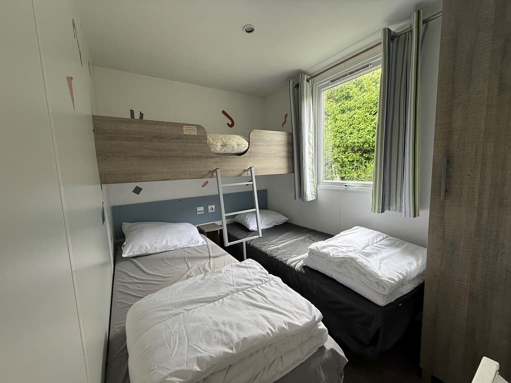 Kamer met twee eenpersoonsbedden, een raam met gordijnen en een kledingkast.