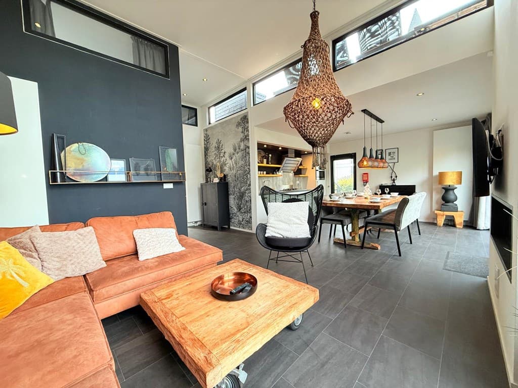 Woonkamer met een grote bank, houten salontafel en eetgedeelte met een moderne inrichting en opvallende decoratie.