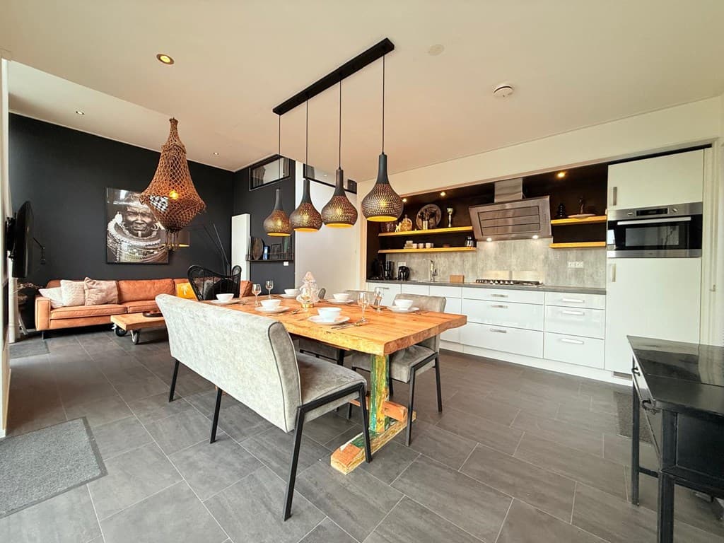 Moderne open keuken en eetruimte met houten tafel, comfortabele bank en sfeervolle verlichting