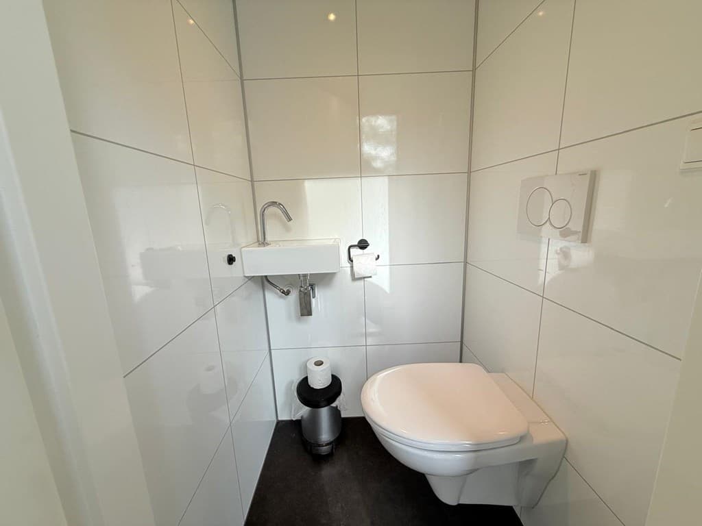 Witte wandtegels in een moderne toiletruimte met een toilet en fonteintje