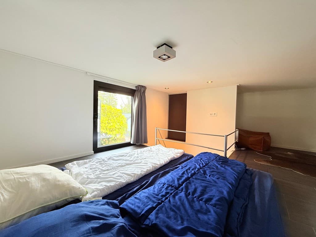 Slaapkamer met twee bedden, raam met uitzicht op buiten en een neutrale inrichting