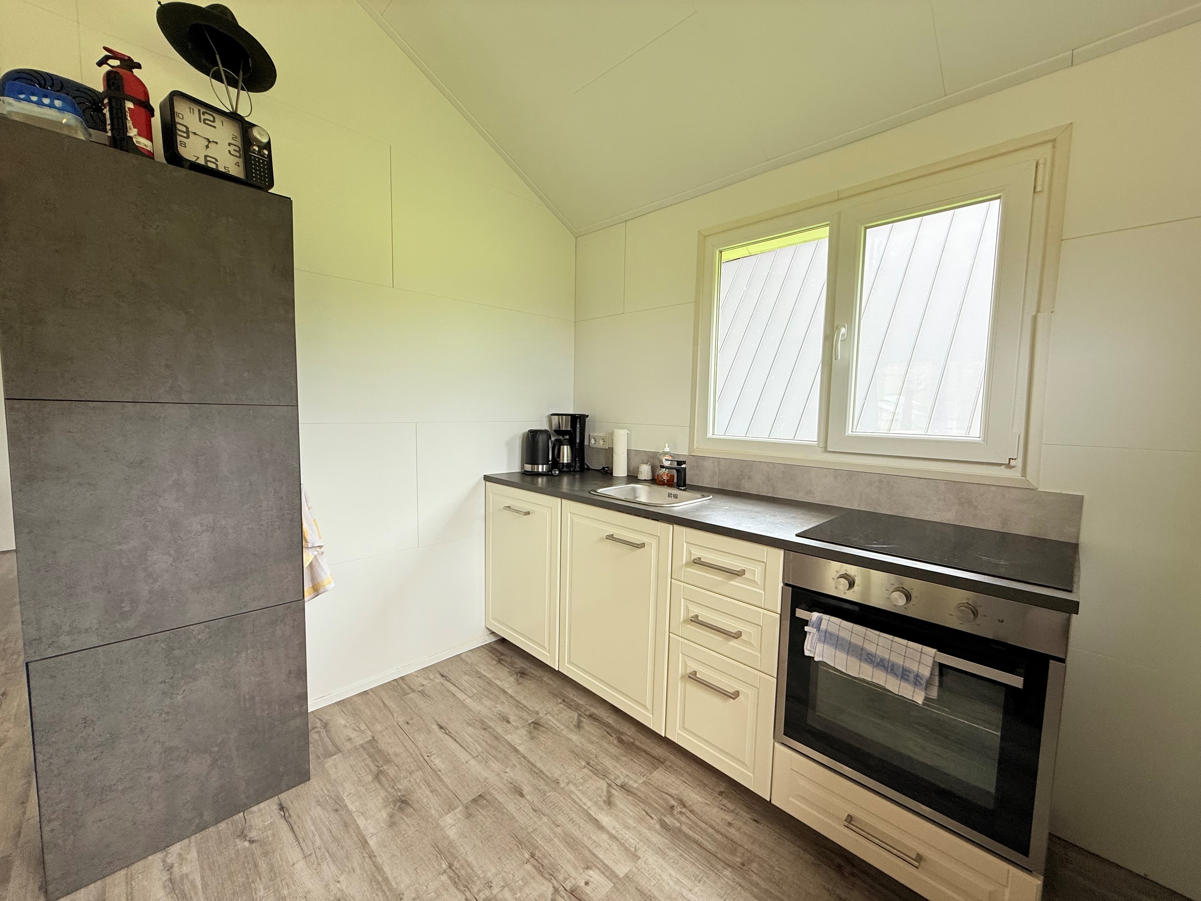 Keuken met moderne kasten, oven, aanrecht en raam met uitzicht op buiten.
