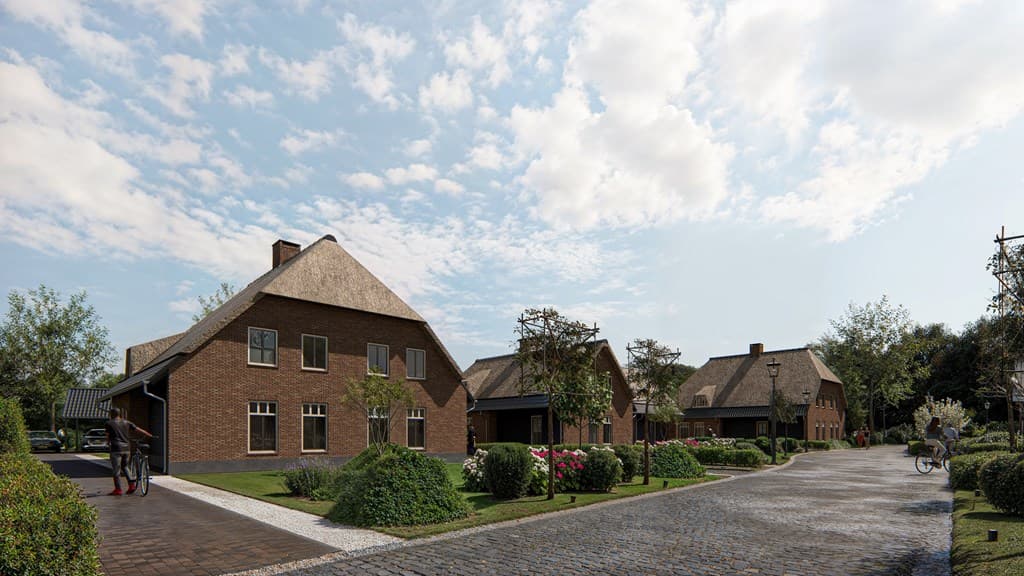 Twee woningen met rieten daken aan een klinkerweg, omgeven door bomen en bloeiende struiken onder een blauwe lucht.