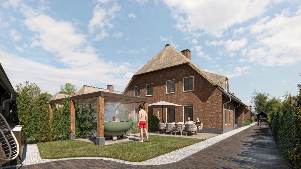 Zijaanzicht van een woning met rieten dak, een terras met zithoek en een houten overkapping met ligbad en parasol.