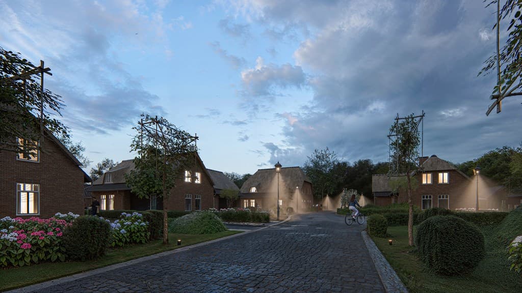 Gezellig straatbeeld met stenen huizen, groene hagen en bloemrijke tuinen onder een bewolkte lucht