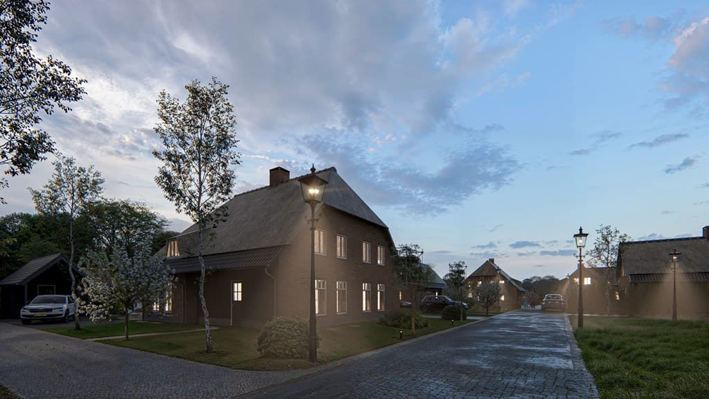 Gezicht op een straat met woningen, omgeven door lampen, bomen en een lichte lucht met wolken in de achtergrond