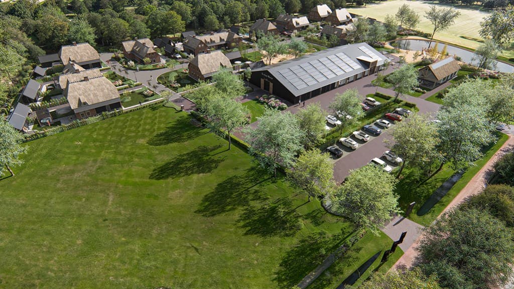 Luchtfoto van een vakantiepark met meerdere woningen, groene tuinen en een centrale parkeerplaats met bomen rondom.