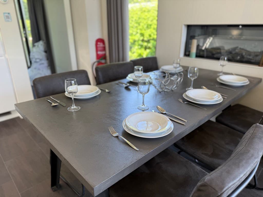 Eettafel met servies en glazen, omgeven door vier stoelen in een lichte ruimte met een moderne uitstraling