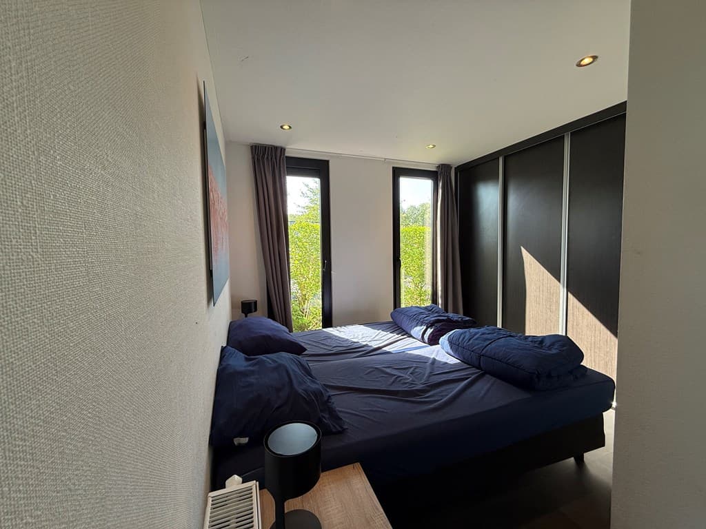 Slaapkamer met twee bedden, grote ramen en inbouwkast, verduisterende gordijnen en ingelichte panelen aan het plafond