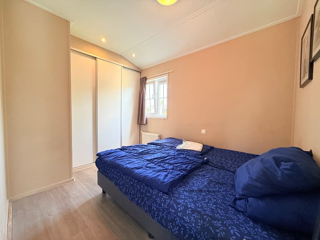 Slaapkamer met twee eenpersoonsbedden, kast en raam voor natuurlijk licht in een vakantiehuis.