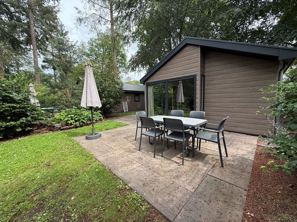 Privé terras met een eettafel en stoelen, omringd door groen en bomen bij een vakantiehuis in Maarn