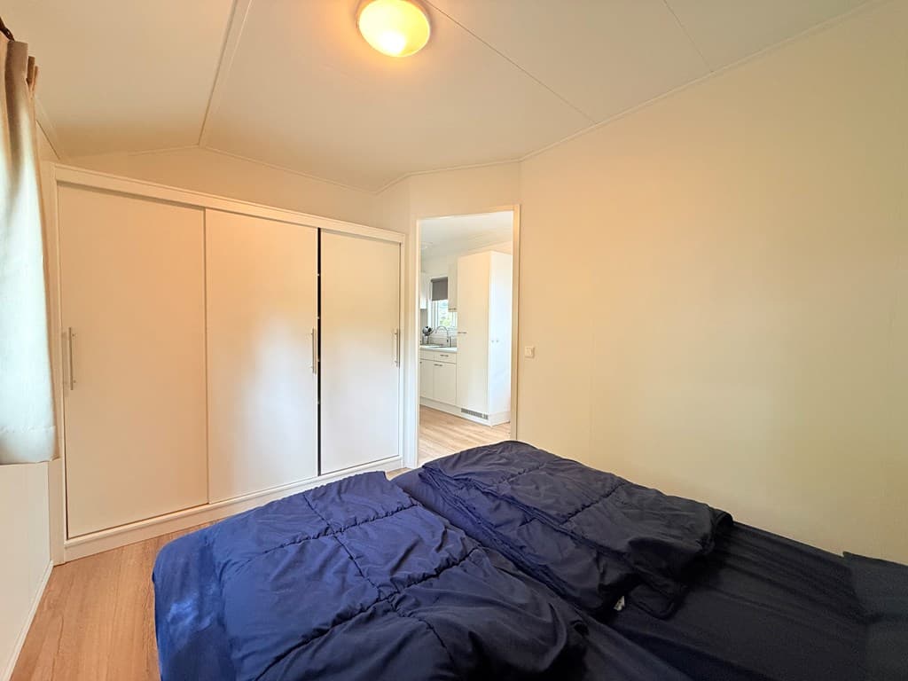 Slaapkamer met twee aparte bedden, kledingkast en zicht op een gang naar de keuken