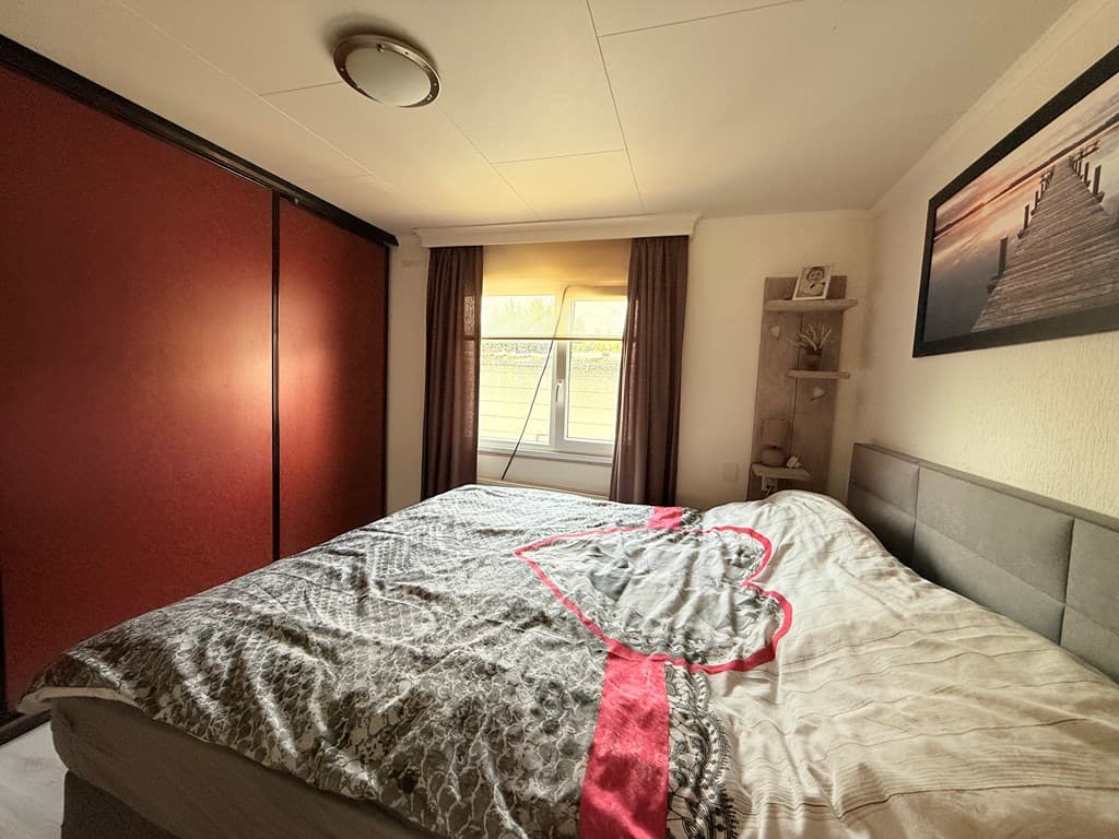Slaapkamer met tweepersoonsbed, ramen met uitzicht en een kledingkast tegen de wand