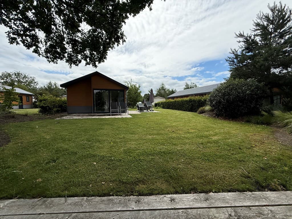 Vakantiewoning met ruime tuin, grasveld en terassen, omgeven door bomen en andere woningen in EuroParcs Zuiderzee.