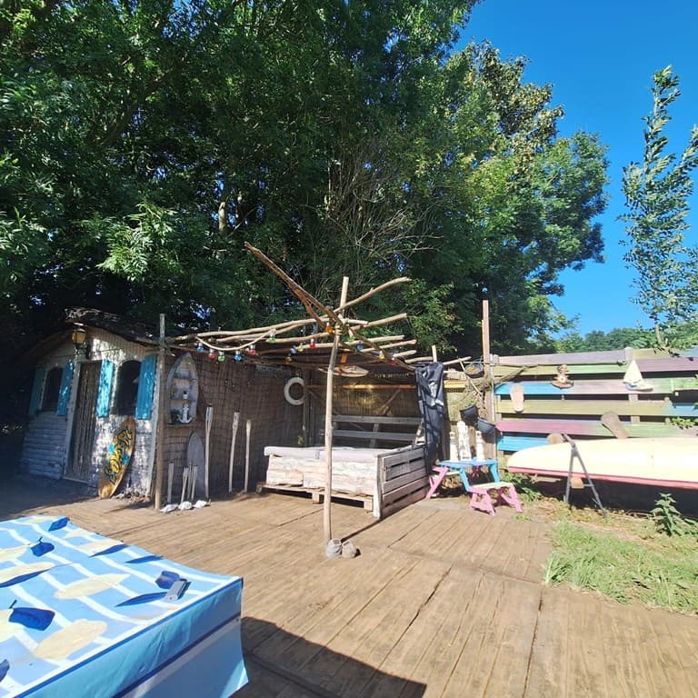 Buitenkant van een vakantiehuisje met een houten terras, decoratieve elementen en groene bomen rondom