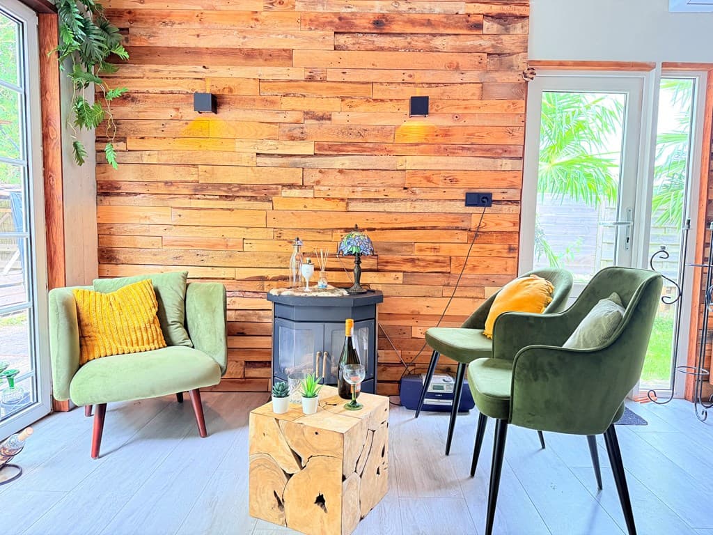 Gezellige zithoek met groene fauteuils, een houten wand, een tafeltje en een sfeerverlichting.