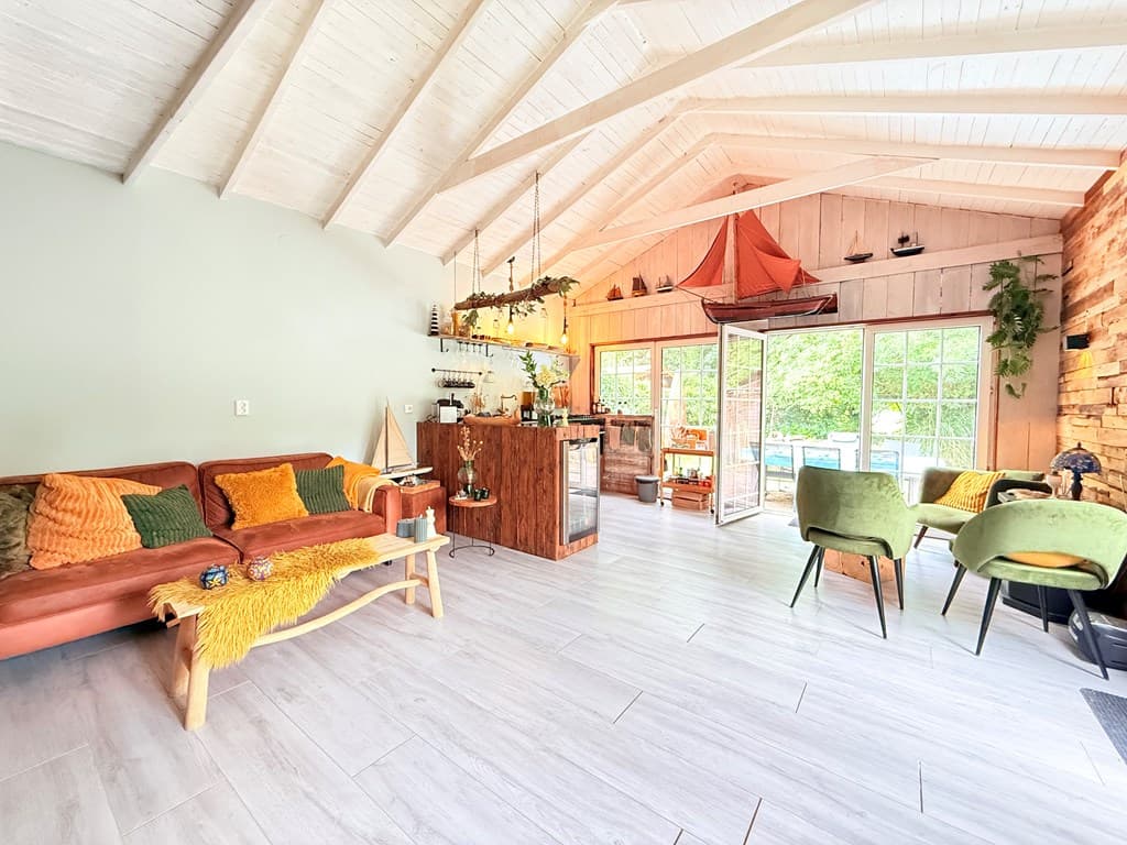 Ruimtelijk interieur met een woonkamer, keuken en een grote glazen schuifdeur naar buiten, voorzien van een hoge houten plafo