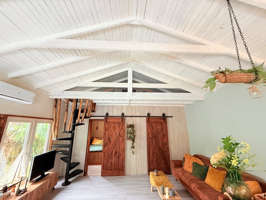 Houten interieur met hoge, witte balkenplafond, gezellige zithoek en schuifdeuren van hout.