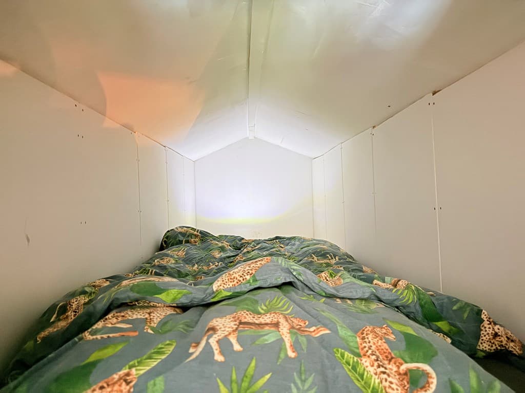 Slaapruimte met een bed bedekt met een dekbed met dierenmotief en een lichte, heldere wand.
