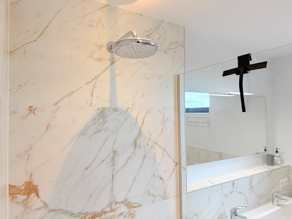 Moderne badkamer met marmerlook tegels, inloopdouche en dubbele wastafel met spiegel en verlichting
