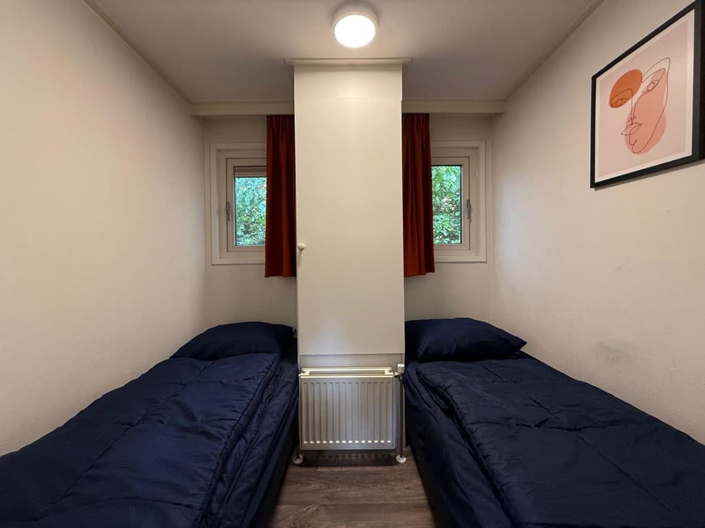 Slaapkamer met twee eenpersoonsbedden, een verwarming en kunstwerk aan de muur.
