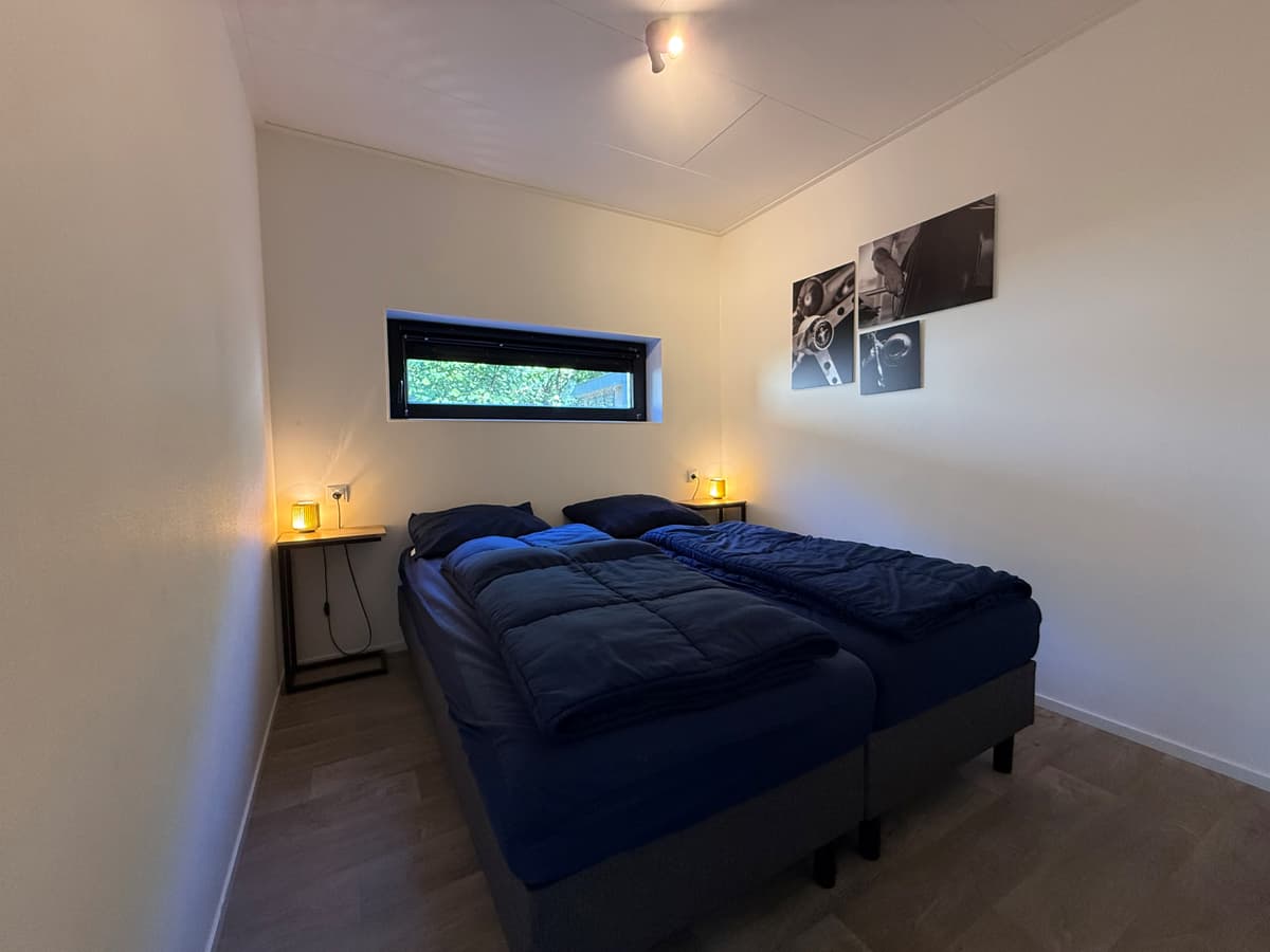 Slaapkamer met twee eenpersoonsbedden, nachtkastjes met lampen en een klein raam aan de muur.
