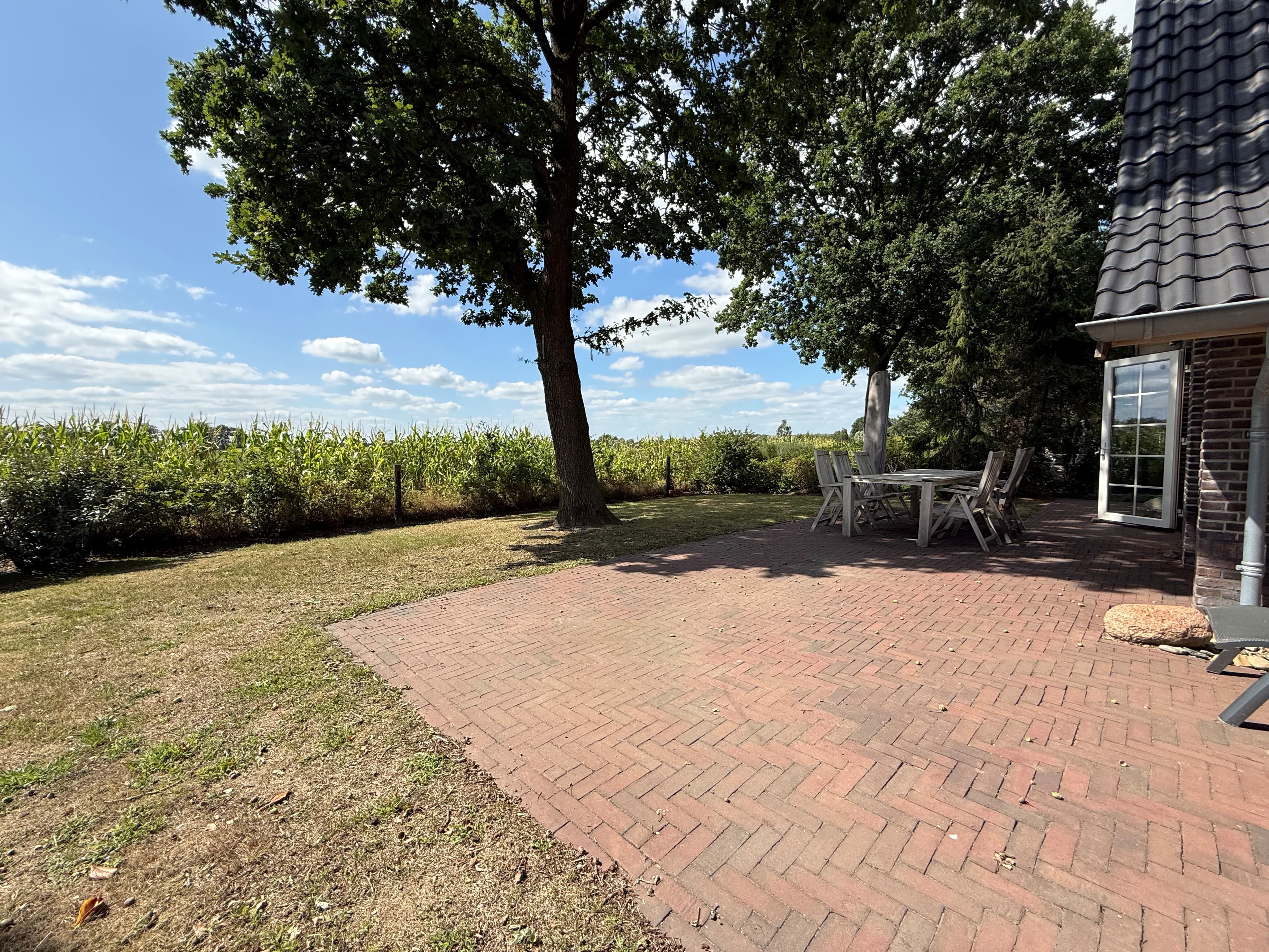 Terras met bomen en uitzicht op akkerland met blauwe lucht en wolken in de achtergrond